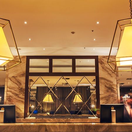 马拉蓬迪温莎酒店 里约热内卢 外观 照片 The photo shows a hotel lobby or reception area. There are large geometric light fixtures hanging from the ceiling, providing a warm glow to the space. The reception desk is made of a polished material, likely marble, with decorative elements and two